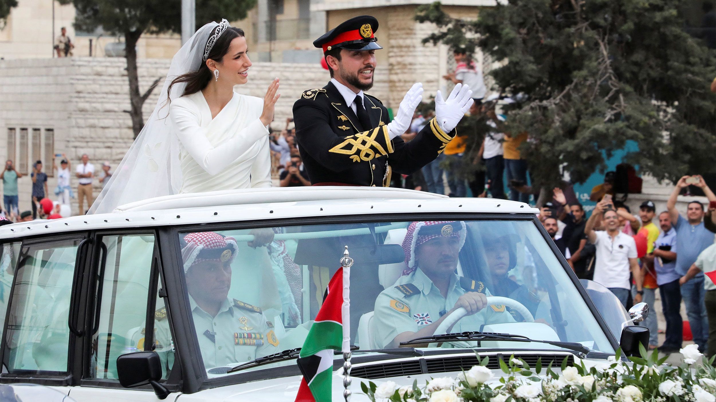 Jordan's Crown Prince Hussein (right) and Rajwa Alseif wave to crowds on their wedding day in Amman.