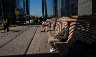 People rest in the sun along the High Line on a sunny and unusually warm day in New York City on October 21.